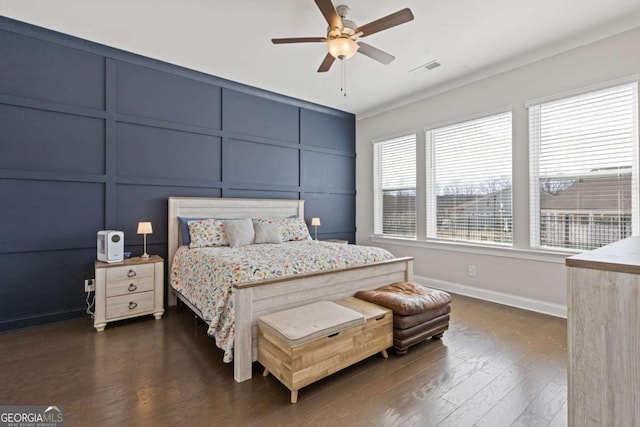 bedroom with dark wood-style floors, baseboards, visible vents, and a decorative wall