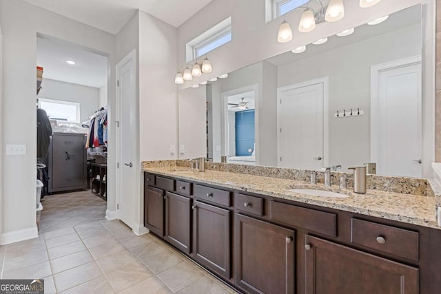 full bathroom featuring double vanity, a sink, a walk in closet, and baseboards