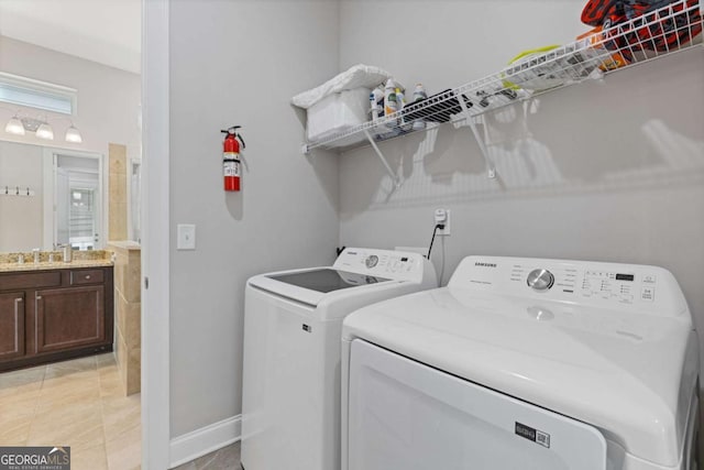 laundry room with light tile patterned floors, laundry area, a sink, and washing machine and clothes dryer