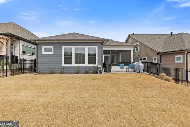 back of property with roof with shingles, a lawn, a sunroom, a patio area, and a fenced backyard