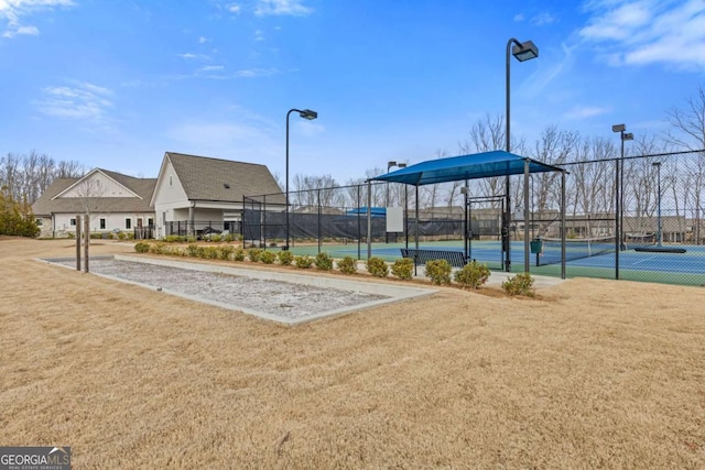 view of community featuring a yard, a gate, a tennis court, and fence