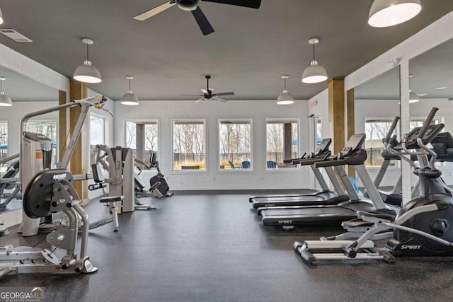 workout area with a healthy amount of sunlight, brick wall, visible vents, and ceiling fan