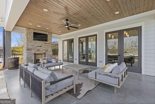 view of patio featuring french doors, an outdoor living space with a fireplace, a ceiling fan, and fence