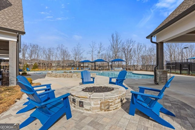 view of patio with a fire pit, fence, a jacuzzi, and a community pool