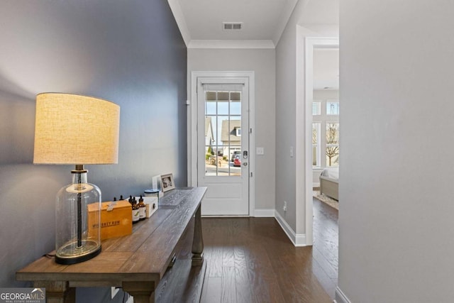 doorway with dark wood-type flooring, visible vents, crown molding, and baseboards