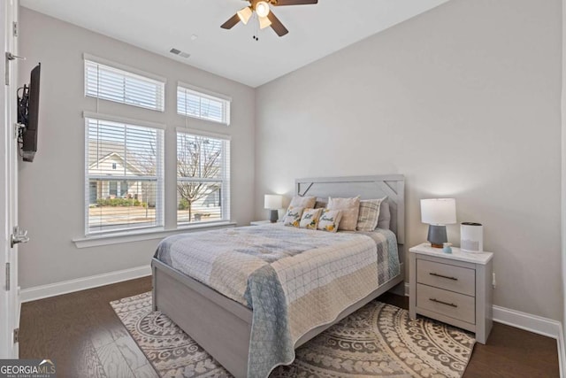 bedroom with multiple windows, wood finished floors, and baseboards