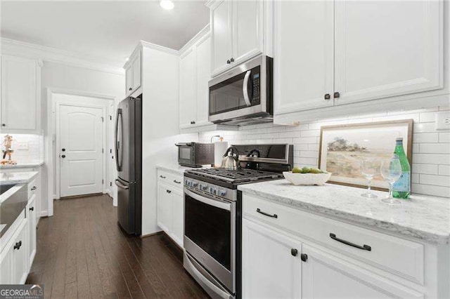 kitchen with stainless steel appliances, light stone counters, and white cabinetry