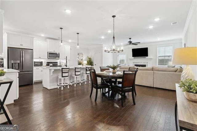 dining space featuring dark wood-style flooring, crown molding, a fireplace, recessed lighting, and visible vents