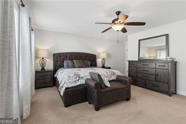 bedroom with a ceiling fan, light carpet, and baseboards