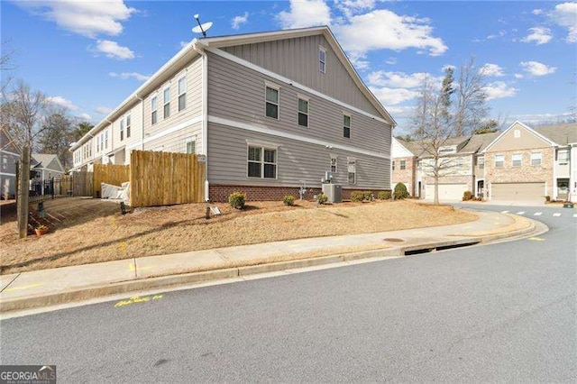 view of home's exterior featuring central AC, brick siding, fence, and a residential view