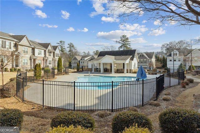 community pool featuring a residential view, fence, and a patio