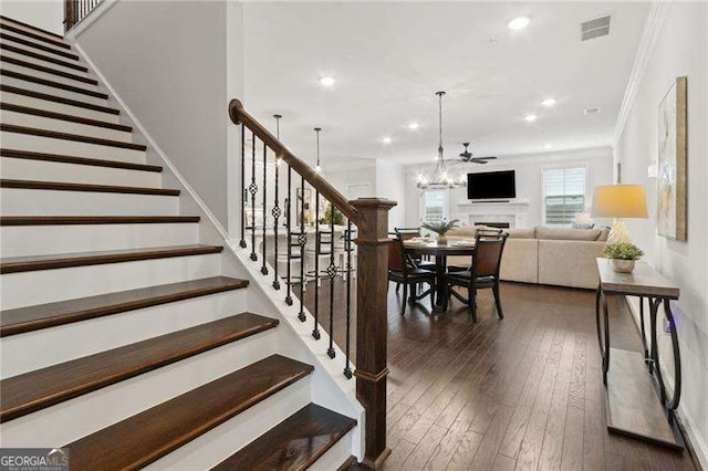 staircase featuring a chandelier, hardwood / wood-style flooring, recessed lighting, visible vents, and ornamental molding