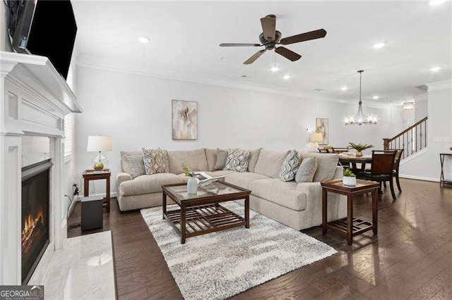 living room featuring ornamental molding, recessed lighting, ceiling fan with notable chandelier, and a premium fireplace