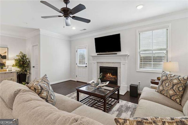 living area featuring a warm lit fireplace, ornamental molding, wood finished floors, and baseboards