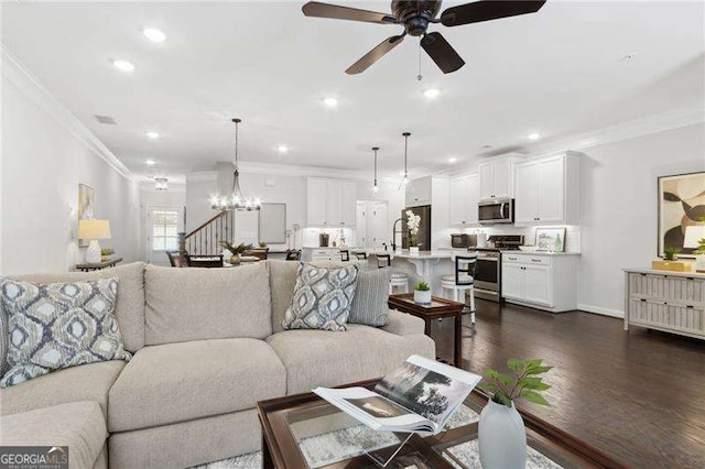 living room with recessed lighting, ceiling fan with notable chandelier, ornamental molding, stairway, and dark wood finished floors