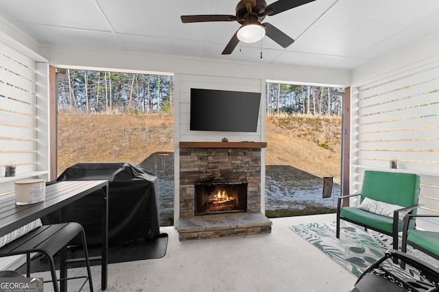 interior space with plenty of natural light, concrete floors, an outdoor stone fireplace, and a ceiling fan