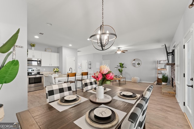 dining space with recessed lighting, visible vents, baseboards, light wood-style floors, and ceiling fan with notable chandelier