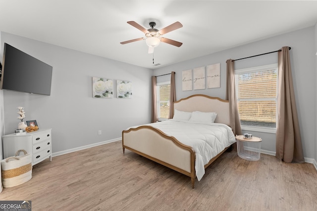 bedroom with multiple windows, light wood-style flooring, and baseboards