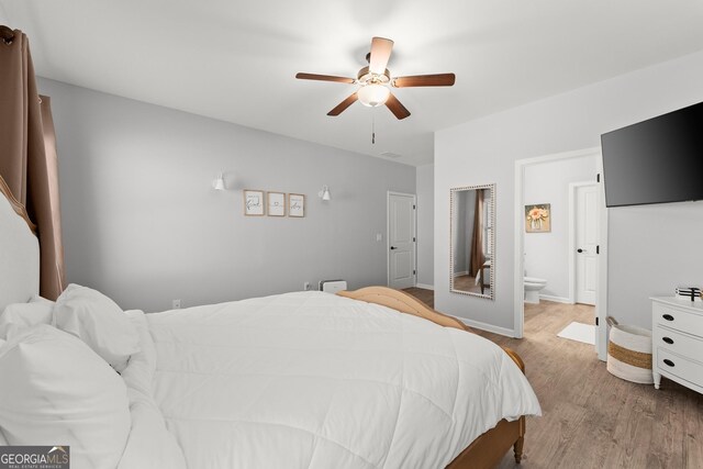 bedroom with a ceiling fan, connected bathroom, baseboards, and wood finished floors