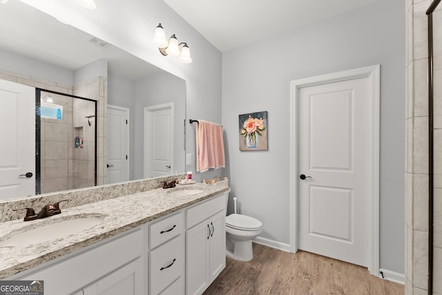 full bathroom with toilet, wood finished floors, visible vents, a sink, and a stall shower