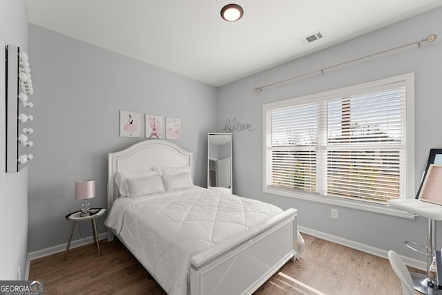 bedroom featuring wood finished floors, visible vents, and baseboards