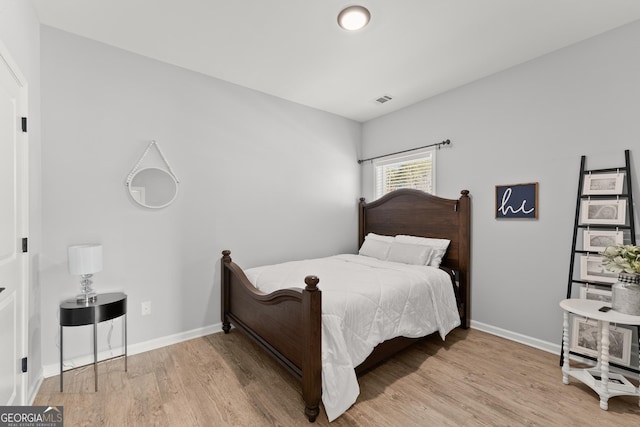 bedroom with baseboards, visible vents, and wood finished floors