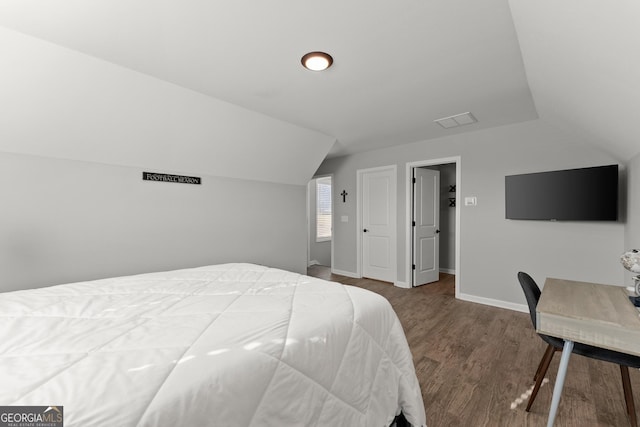 bedroom with vaulted ceiling, baseboards, and wood finished floors