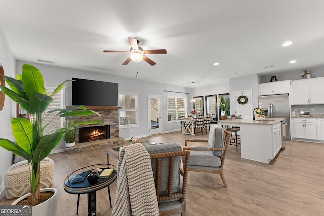 living room featuring recessed lighting, a fireplace, visible vents, and light wood-style floors