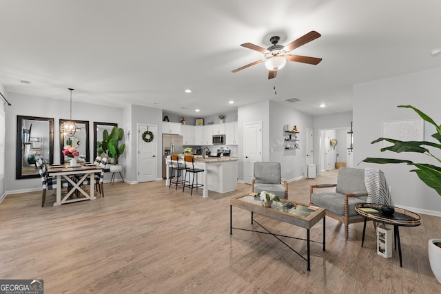 living room with recessed lighting, visible vents, light wood-type flooring, baseboards, and ceiling fan with notable chandelier