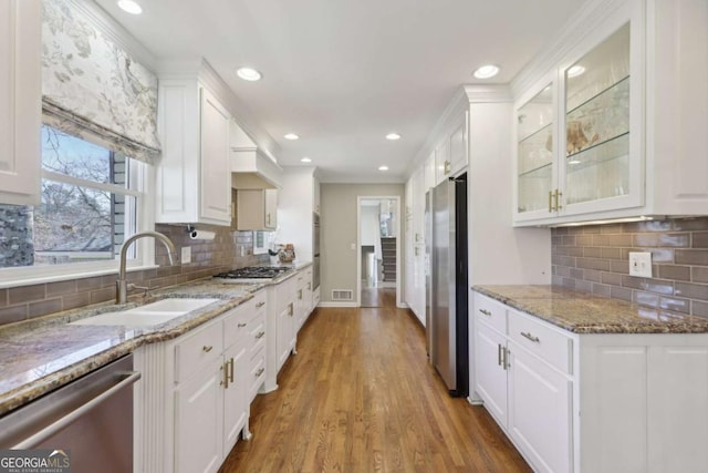 kitchen featuring a sink, white cabinets, glass insert cabinets, and stainless steel appliances