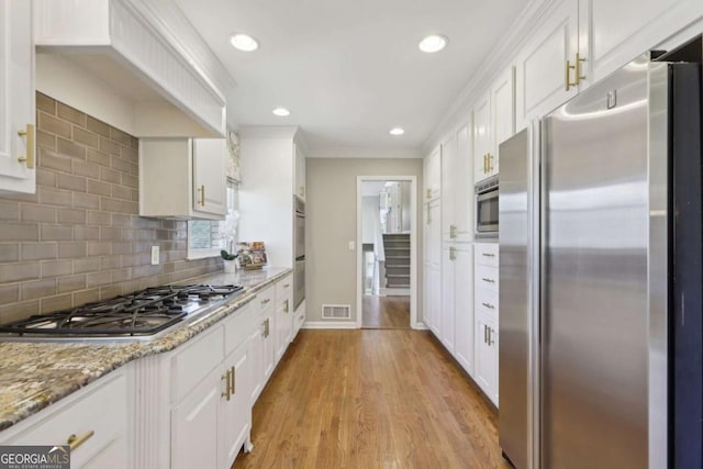 kitchen with visible vents, light wood-style floors, appliances with stainless steel finishes, and white cabinetry