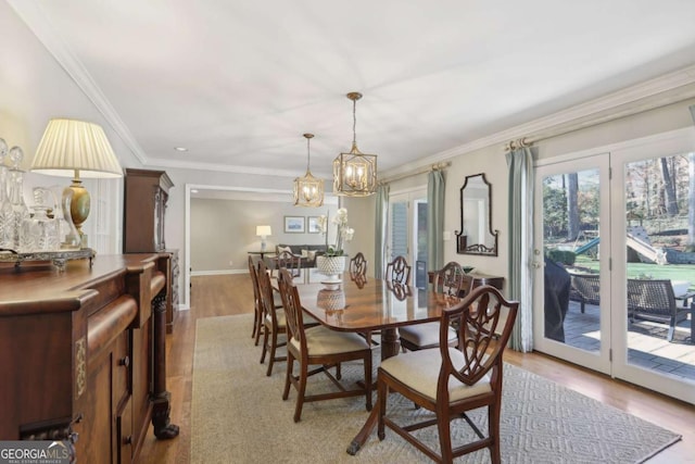 dining space featuring crown molding, baseboards, light wood-type flooring, and an inviting chandelier