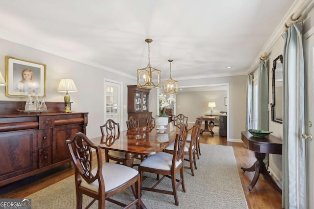 dining room with an inviting chandelier, crown molding, wood finished floors, and baseboards