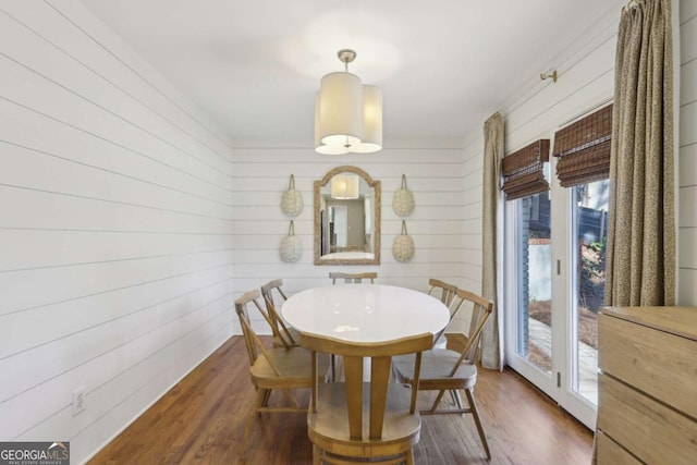 dining space featuring wood walls and dark wood-type flooring