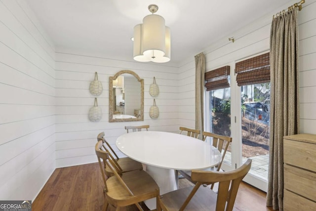 dining area with wood walls and dark wood-type flooring