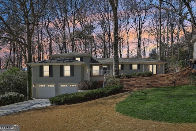 view of front facade with a garage, a yard, concrete driveway, and brick siding