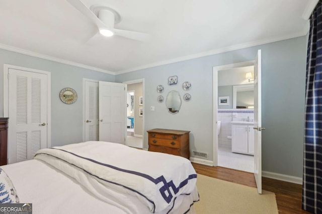 bedroom featuring baseboards, wood finished floors, visible vents, and ornamental molding