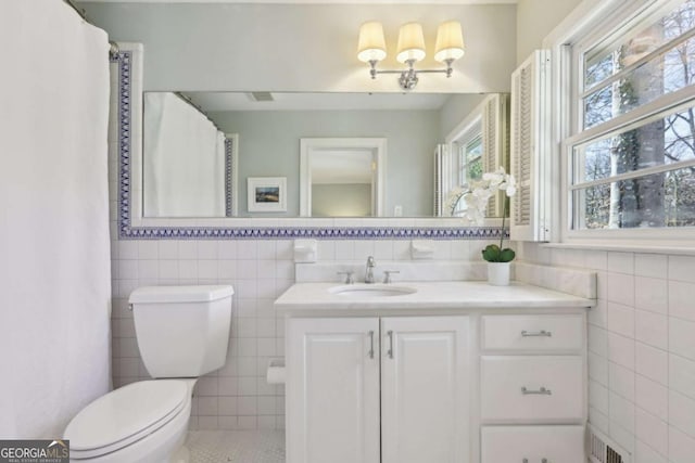 full bathroom with visible vents, toilet, tile walls, and vanity