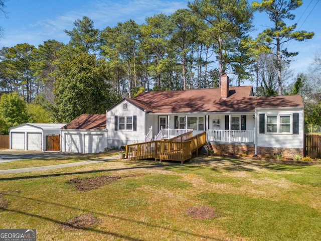 back of house with a detached garage, a porch, a lawn, a chimney, and an outdoor structure