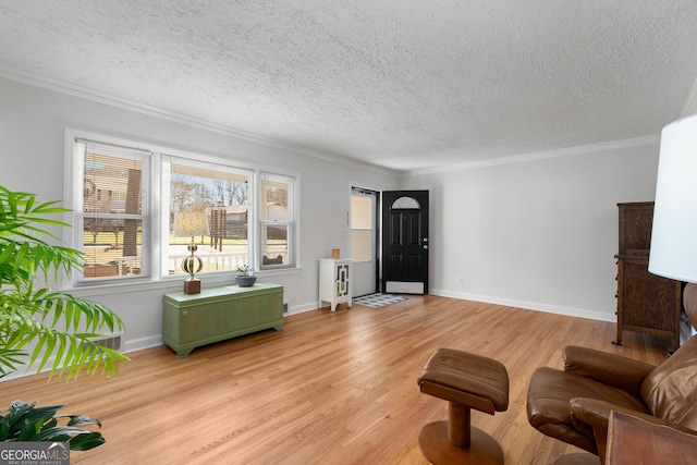 living area featuring a textured ceiling, light wood-style floors, baseboards, and ornamental molding