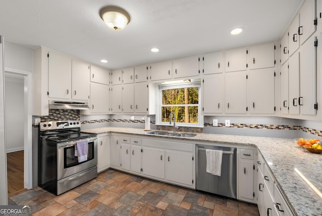 kitchen featuring backsplash, stone finish flooring, extractor fan, stainless steel appliances, and a sink