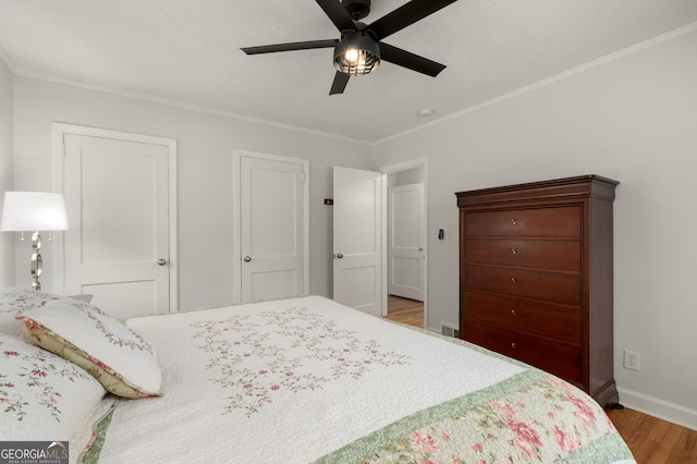 bedroom with baseboards, wood finished floors, a ceiling fan, and ornamental molding