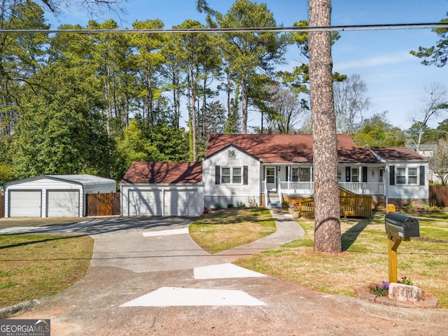 view of front of property featuring a porch, a detached garage, and a front yard