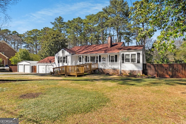 back of house featuring fence, a chimney, an outdoor structure, a detached garage, and a lawn