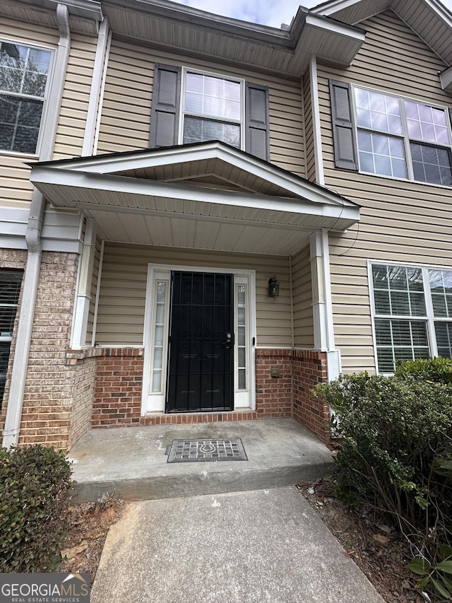 doorway to property with covered porch and brick siding