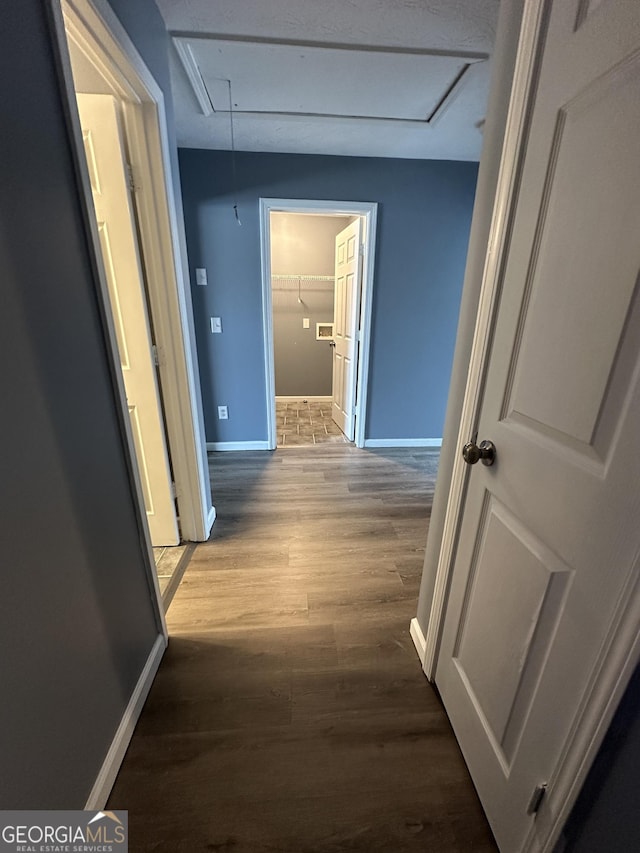 hall featuring attic access, baseboards, and wood finished floors