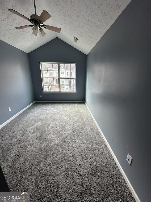 spare room with lofted ceiling, a textured ceiling, ceiling fan, carpet floors, and visible vents