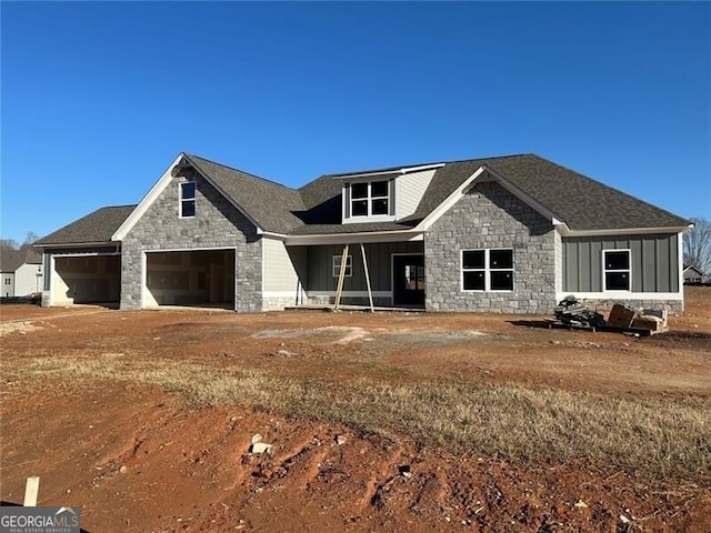 view of front of home featuring driveway, a garage, board and batten siding, and stone siding