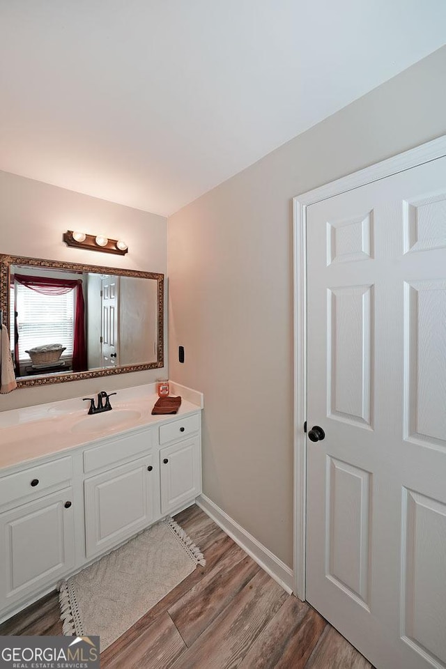 bathroom featuring baseboards, wood finished floors, and vanity