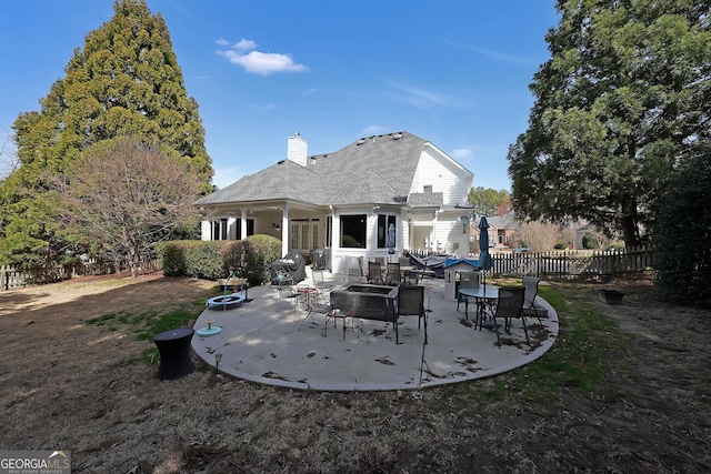 rear view of property featuring a patio area, fence, a chimney, and an outdoor fire pit